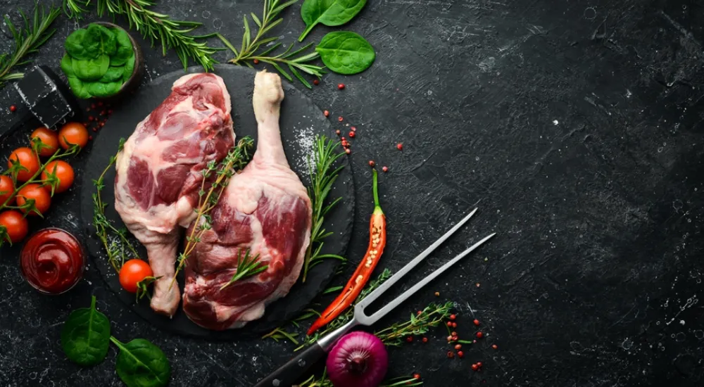 Duck Meat Near Me | Piece of duck meat on a slate board with vegetables around it.